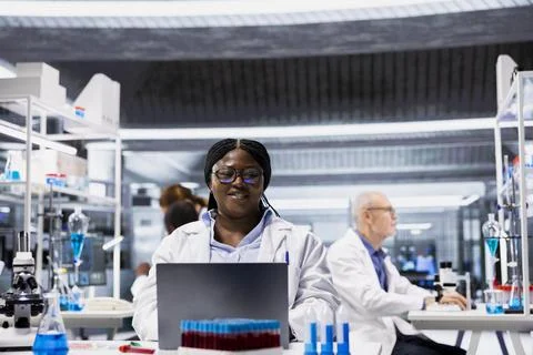 Portrait of smiling scientist typing data in laptop software at laboratory desk Stock Photos