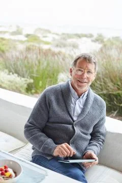 Portrait smiling senior man using digital tablet on beach patio Stock Photos