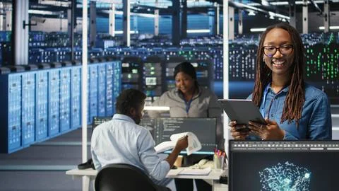 Portrait of smiling server room engineer using device to interpret AI data Stock Photos