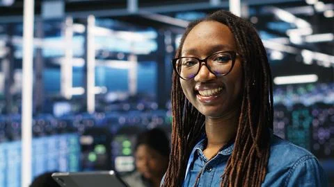 Portrait of smiling server room engineer using device to interpret AI data Foto stock
