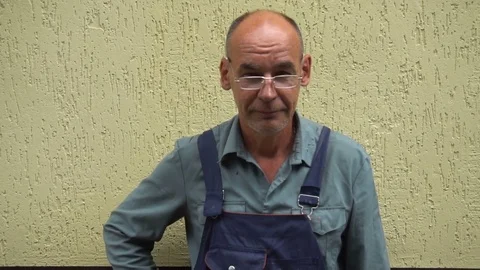Portrait of a smiling shoemaker in glasses standing against the yellow wall Stock Footage 77921302