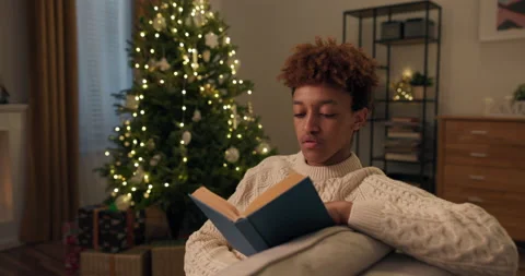 Portrait of a smiling smart boy dressed in a warm winter sweater, reading a book Stock Footage 210242683