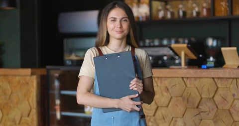 Portrait of smiling waitress in apron with tablet in hands standing and looking Video stock 163844013