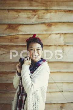 Portrait smiling woman with camera outside cabin Stock Photos