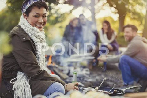 Portrait smiling woman drinking beer with friends at campfire Stock Photos