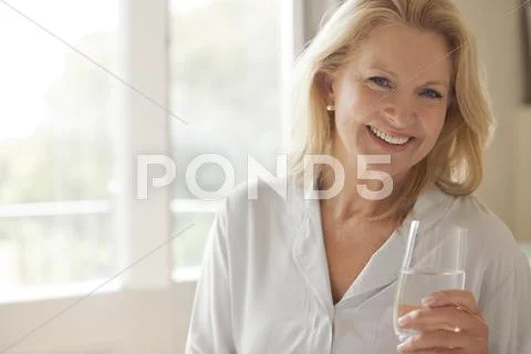 Portrait Of Smiling Woman Drinking Glass Of Water