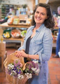 Portrait smiling woman with flowers in basket shopping in market Stock Photos