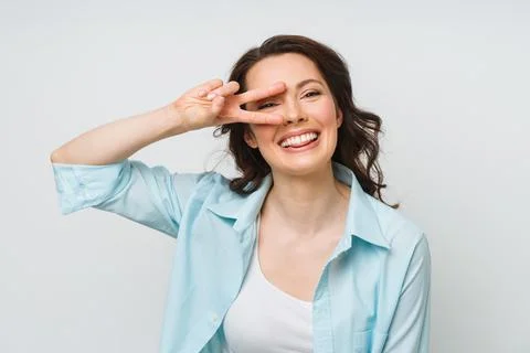Portrait of a smiling woman showing a victory sign and looking into a camera Stock Photos