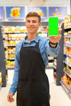 Portrait of a smiling worker man in apron black color standing in the Stock Photos