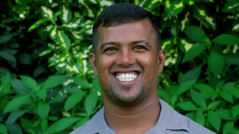 Portrait of a smiling worker standing in front of green leaves Видео 318025441