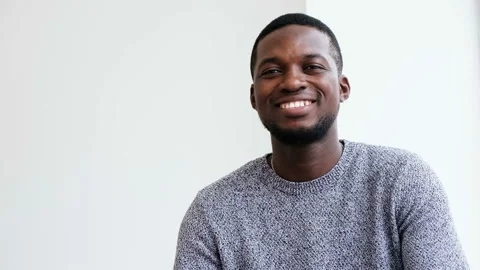 Portrait of smiling young African guy looking at camera isolated at white studio Stock Footage 109155694