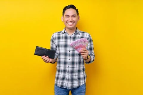 Portrait of smiling young Asian man wearing plaid shirt holding a wallet an.. Stock Photos
