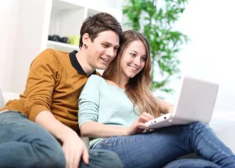 Portrait of a smiling young couple using laptop at home indoor Stock Photos