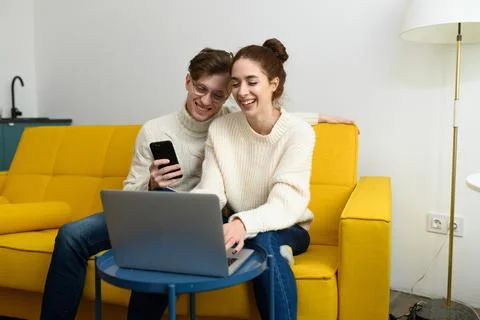 Portrait of a smiling young couple using laptop at home indoor 库存照片