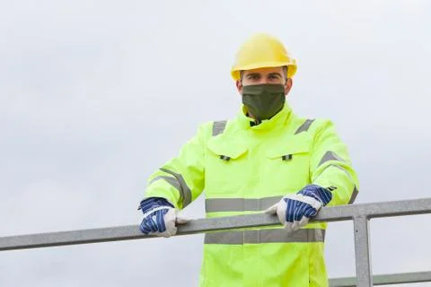 Portrait of smiling young engineer or worker with face mask and hard hat Stock Photos