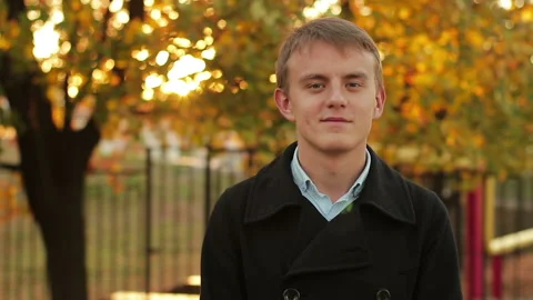 Portrait of a smiling young guy in the fall at sunset Stock Footage 96267675