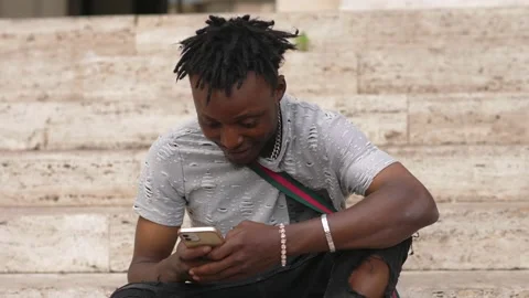 A portrait of a smiling young man texting with her phone on the stairs Stock-Footage 218601321