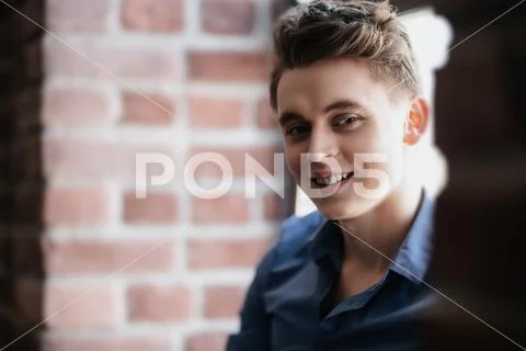 A portrait of a smiling young man wearing a blue shirt and posing indoor. Men Stock Photos