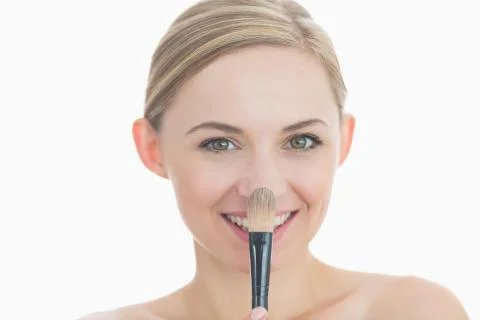 Portrait of smiling young woman putting on make-up Stock Photos