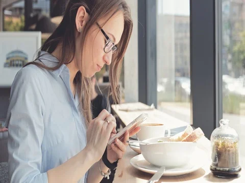 Portrait of Smiling Young Woman Using Smart Phone in a Cafe. 4K SLOW MOTION DCi Stock Footage 79365538