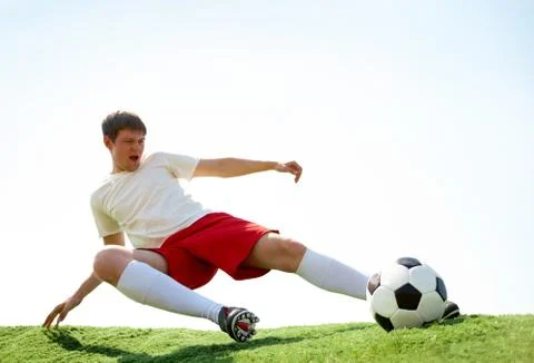 Portrait of soccer player kicking ball during game Stock Photos