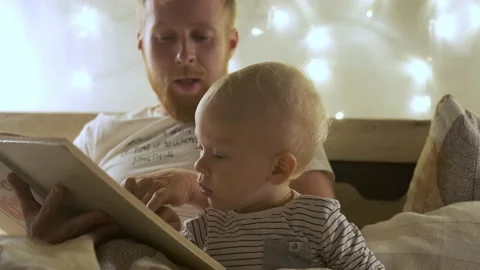 Portrait with son reading a book father on bed in the evening 스톡 동영상 163638436