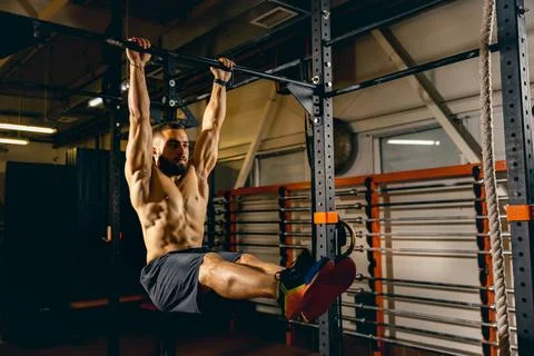 Portrait of sportive man doing pull-up exercises. Developing muscles. Gym Foto stock