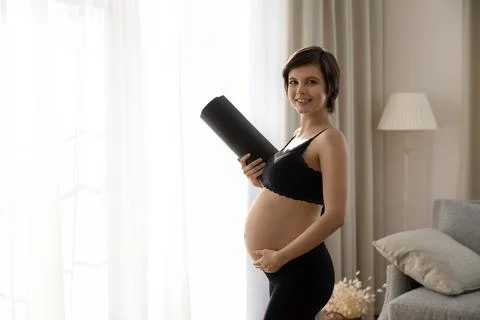 Portrait of sporty pregnant female with rolled mat under hand Stock Photos