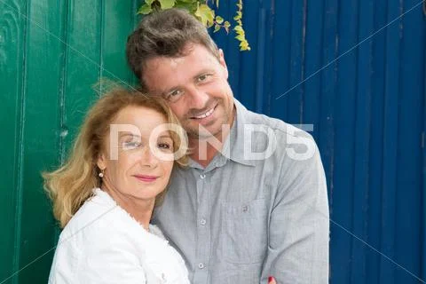 Portrait of a standing cute couple with arms around Stock Photos