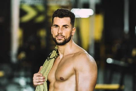 Portrait of strong man facing the camera with a towel in the shoulder in a gym Stock Photos