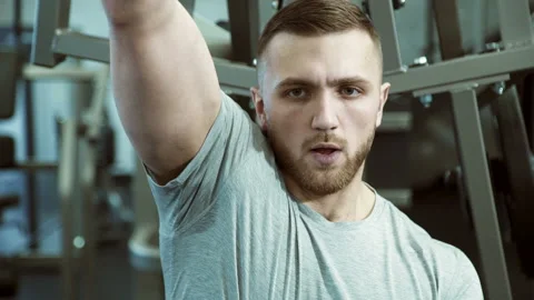 Portrait of a strong man who pulls weight with one hand on a training machine. Stock Footage 89041961