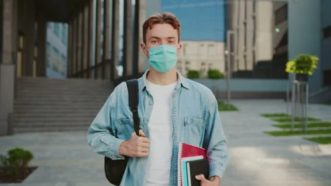 Portrait student in a mask look at camera hold books. Stand on street near Stock Footage 142048758