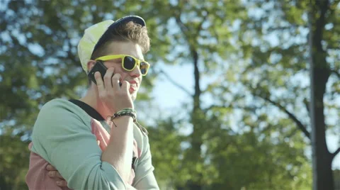 Portrait of a stylish cheerful boy talking on phone, outdoors. 動画素材 42990663