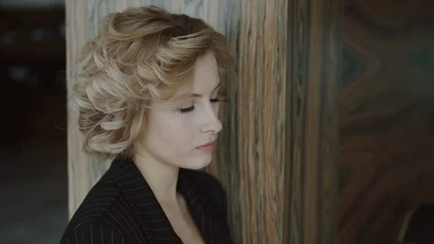 Portrait of stylish lady leaned on wall, looks aside and thinking indoors 库存影片 125032475