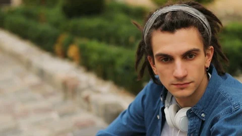 Portrait of stylish man with dreadlocks and headphone on the neck smiling on the Stock Footage 79446627