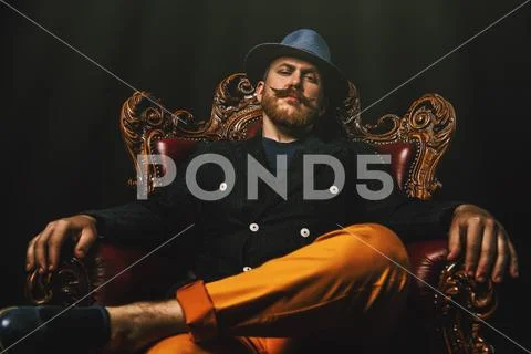 A portrait of a stylish modern man posing in the armchair. Men fashion, style Stock Photos