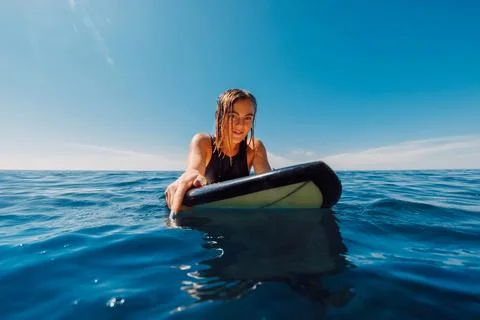 Portrait of surf girl on surfboard. Beautiful blonde woman look at camera on  Stock Photos