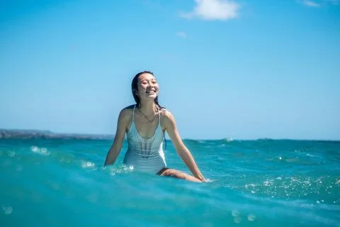Portrait of surfer girl on surf board in blue ocean Stock Photos