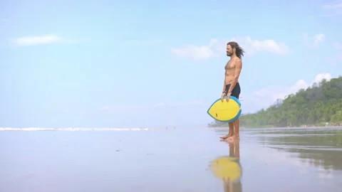 Portrait of a surfer man looking at ocean. Millennial guy with surfboard  Stock Footage 150053747