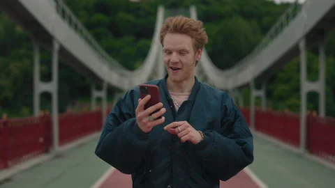 Portrait of surprised man walking on bridge and using mobile Stock Footage 162733112