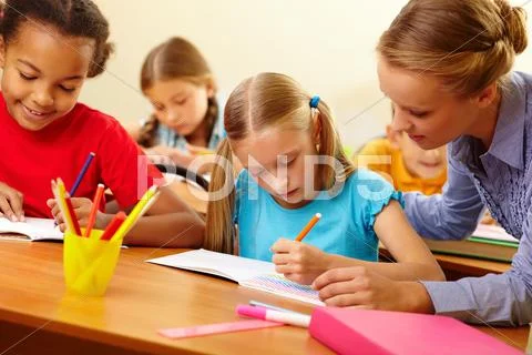 Portrait of teacher looking at a drawing schoolgirls copybook at lesson Stock Photos