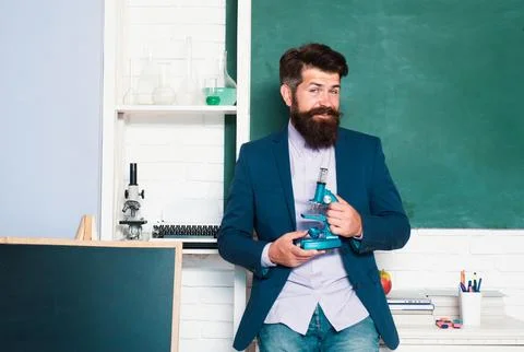 Portrait of teacher man hold microscope at school in classroom at school. Stock Photos