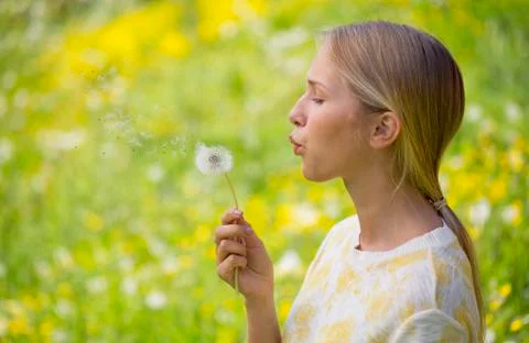 Portrait of teenage girl blowing blowball on a flower meadow Stock Photos