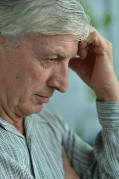 Portrait of an thinking elderly man on a gray background Stock Photos