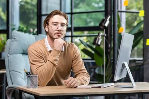 Portrait of thinking serious man with computer inside modern green loft office Foto stock