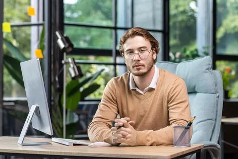 Portrait of thinking serious man with computer inside modern green loft office 写真素材