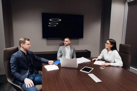 Portrait of three co-workers discussing business plan in office Stock Photos