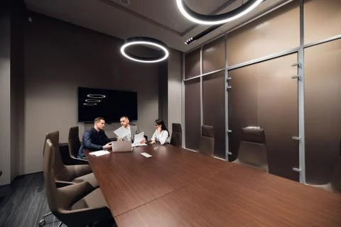 Portrait of three co-workers discussing business plan in office Stock Photos