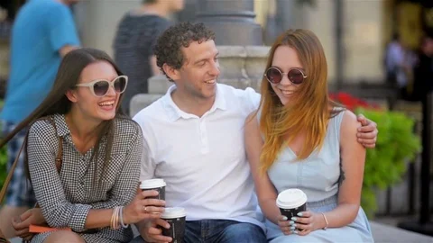 Portrait of Three Friends Drinking Coffee Sitting on the Bench Outdoors in the Stock Footage 79930562