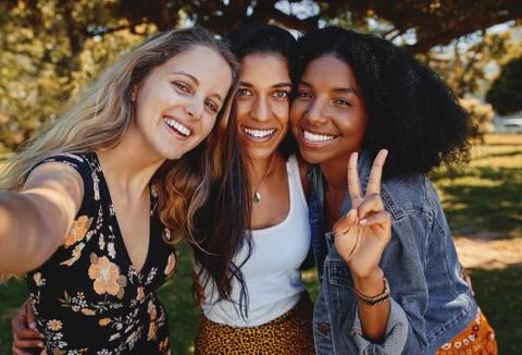 Portrait of three smiling happy multiethnic female friends taking a selfie in Stock Photos